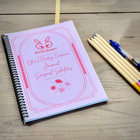 Lavender spiral-bound Book Bunny™ Official Reading Companion Journal – Seasonal Selections on a wooden tabletop.
