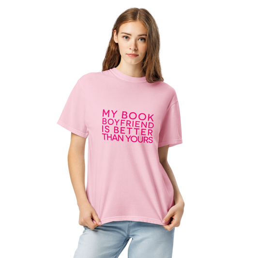 A woman modeling a light pink crewneck t-shirt with the text 'SPREAD THOSE PAGES' printed in bright pink across the chest, paired with light blue jeans against a plain white background.